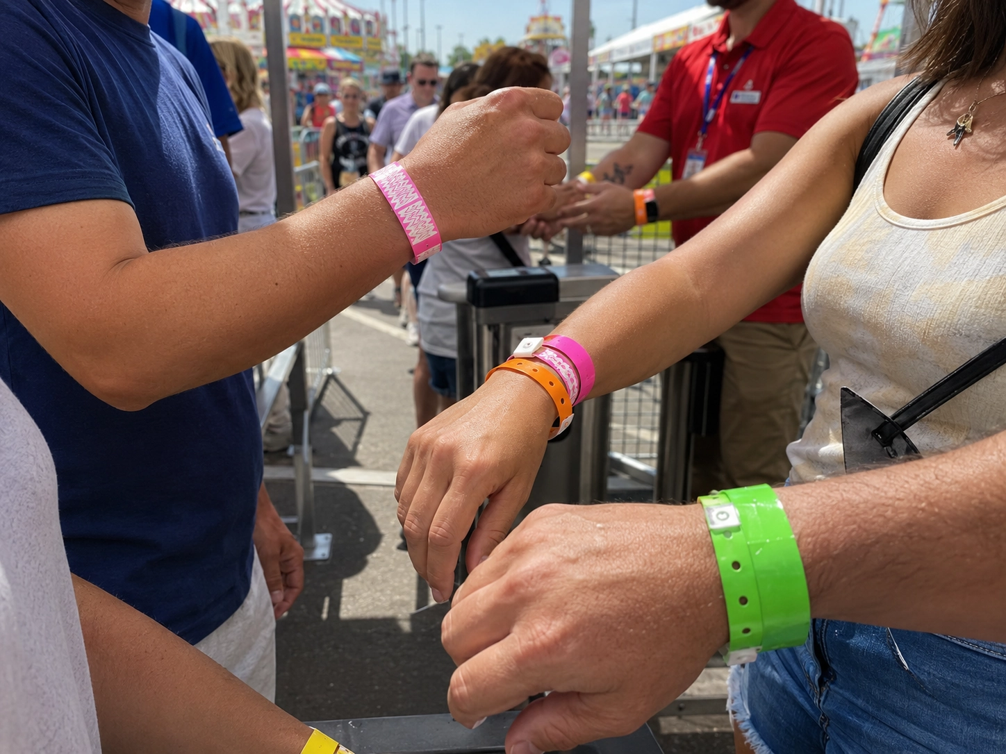 Close-up of guests wearing brightly colored bulk Tyvek and vinyl carnival wristbands at a busy fairgate admission control point, illustrating event budget management and midway access control. Close-up of guests wearing brightly colored bulk Tyvek and vinyl carnival wristbands at a busy fairgate admission control point, illustrating event budget management and midway access control.